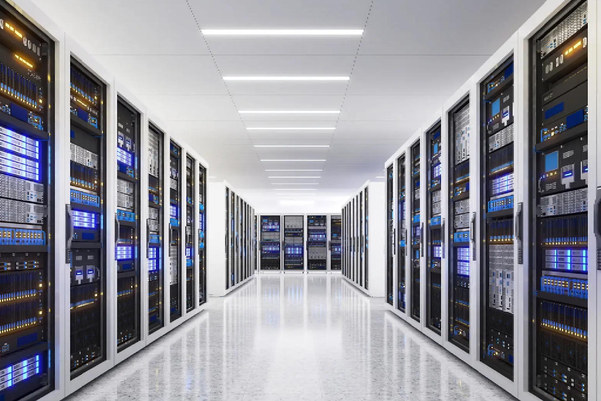 A brightly lit server room with rows of black and white server racks on both sides and digital displays showing blue lights.
