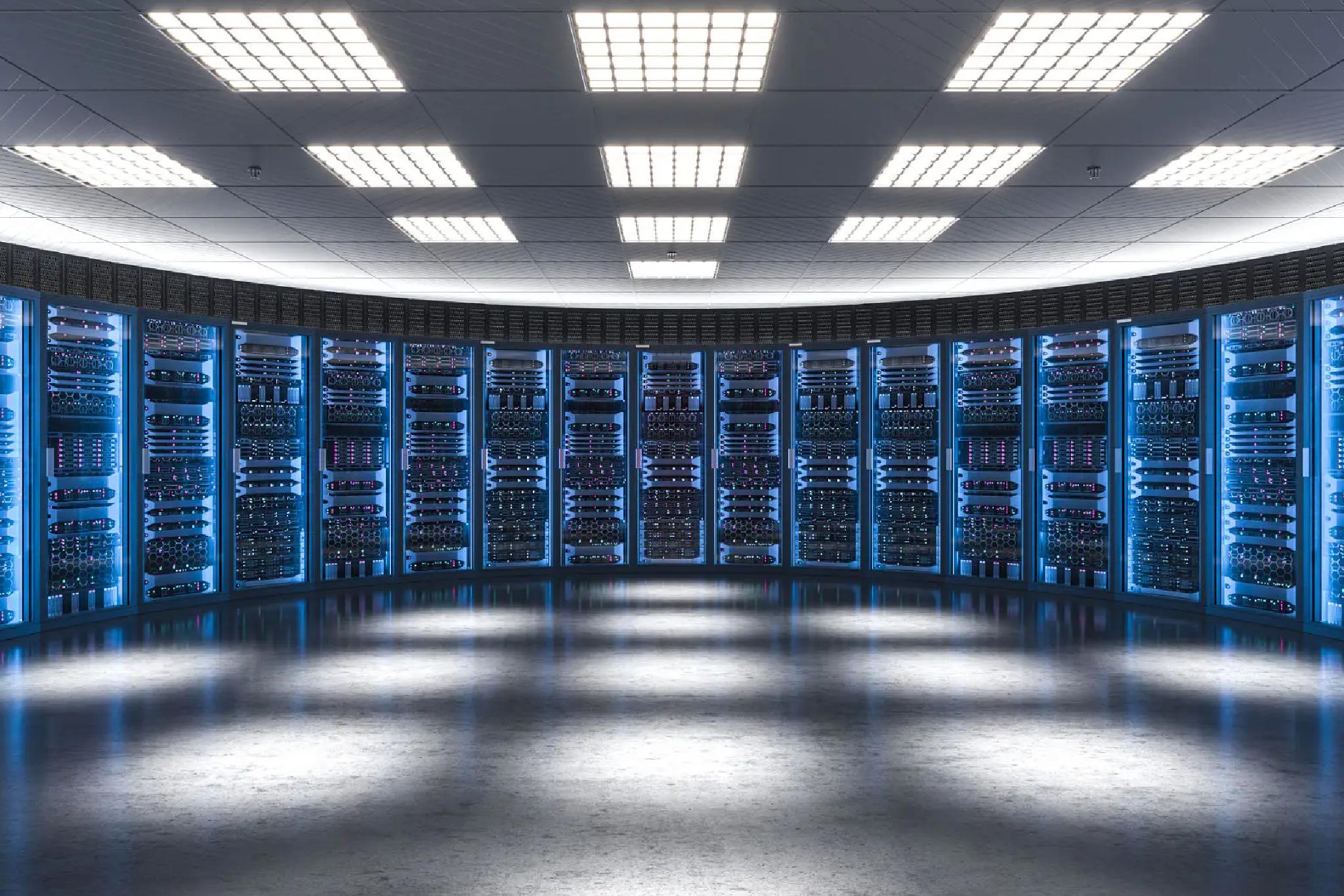 A large, curved room filled with rows of illuminated blue server racks under bright ceiling lights.
